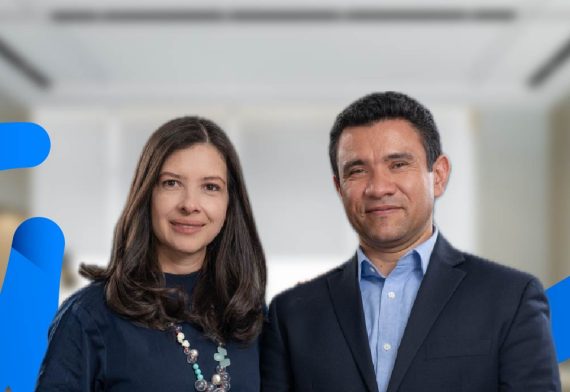 izquierda de la pantalla una mujer con vestido oscuro y a su derecha un hombre con traje. De fondo hay una oficina