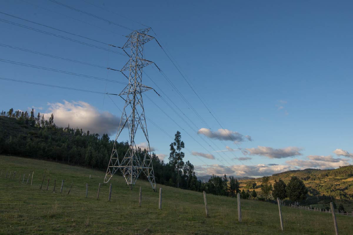 torre energía de ISA sobre un prado verde. De fondo hay un cielo azul